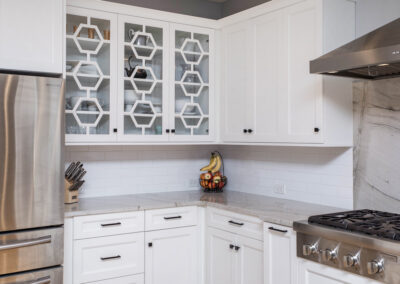 White custom kitchen cabinetry with black hardware and glass doors